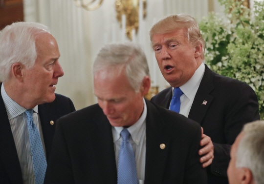 도널드 트럼프(오른쪽) 미국 대통령이 19일 워싱턴 백악관 국무식당에서 공화당 론 존슨(위스콘신·가운데) 상원의원과 존 코닌(텍사스) 상원의원을 맞이하고 있다.