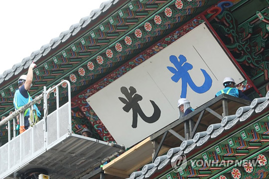 (서울=연합뉴스) 문화재청 직원들이 28일 서울 광화문에서 광화문 현판 색상 분석 연구를 위한 실물 크기 실험용 현판을 설치하고 있다.