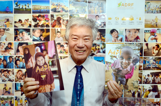 권이종 아프리카아시아난민교육후원회(ADRF) 회장이 1일 서울 용산구 새창로 ADRF 사무실에서 직접 발행한 소식지를 들고 활짝 웃고 있다. 권 회장의 뒤로 ADRF가 후원하는 13개국 아이들의 사진이 보인다.