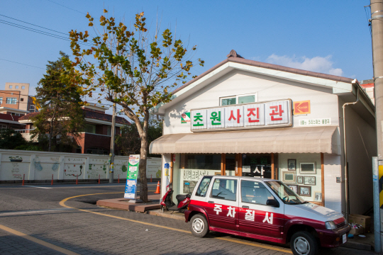 영화 ‘8월의 크리스마스’(왼쪽 사진)의 주인공 남녀가 사랑을 키워가는 공간인 초원사진관은 전북 군산시 버스 차고지에 세트를 지어 만들었다. 촬영 후 철거됐지만 2012년 군산시가 그 자리에 그대로 복원했다.  군산시 제공