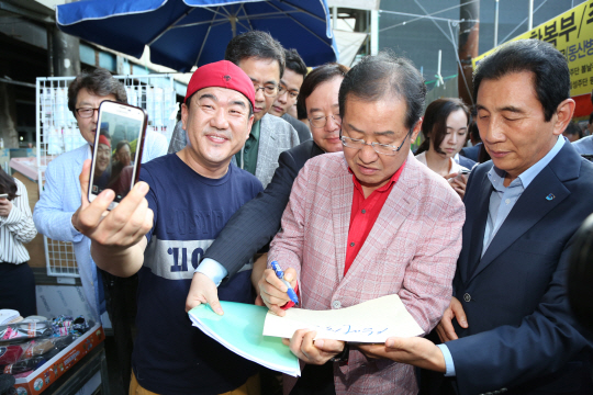 홍준표(오른쪽 두 번째) 자유한국당 대표가 16일 오후 대구 서문시장을 방문해 시민들에게 사인을 해주고 있다. 뉴시스