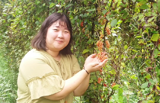 지난 16일 청년 여성 농업인 이소희 씨가 경북 문경시 농암면 청화원 밭에서 탐스럽게 익어가는 오미자 열매를 보여주며 환하게 웃고 있다.