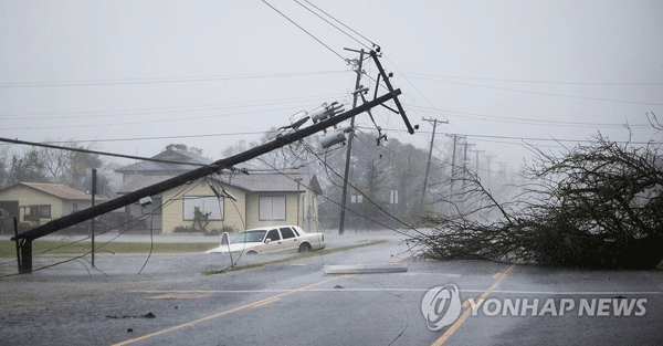 26일(현지시간) 미국 텍사스주 연안 소도시 락포트에서 허리케인 ‘하비’ 영향으로 거리의 전신주가 쓰러져 있는 가운데 차량 한 대가 물에 잠긴채 버려져 있다.[AP=연합뉴스]