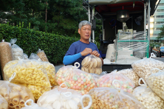 김성한 씨가 지난 19일 서울 종로구 새문안로의 한 거리에서 좌판을 펼쳐 놓고 뻥튀기를 정리하고 있다.  초록우산어린이재단 제공