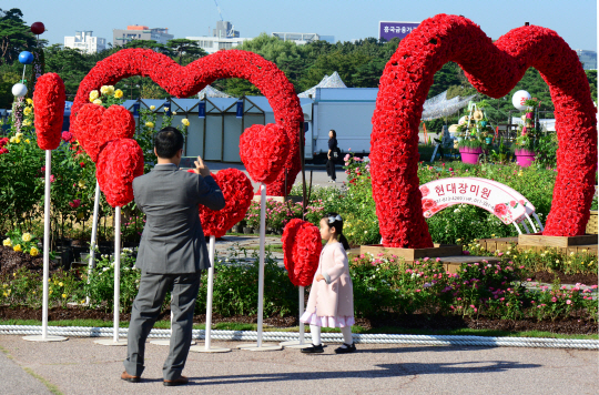 서울시 대표 박람회인 ‘2017 서울정원박람회’ 개막을 하루 앞둔 21일 오전 한 시민이 하트 모양의 장미정원을 촬영하는 중 한 어린이가 그 앞을 지나가고 있다.