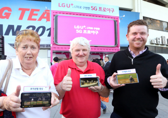 17일 서울 송파구 잠실야구장에 마련된 LG유플러스 체험존에서 외국인들이 4.5세대(G) 네트워크 프로야구 중계를 체험한 뒤 엄지손가락을 치켜들고 있다.  LG유플러스 제공