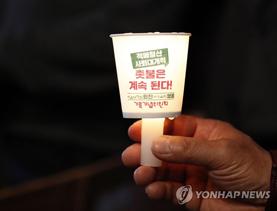 (서울=연합뉴스) 28일 저녁 서울 종로구 광화문 광장에서 박근혜정권퇴진 비상국민행동 기록기념위원회 주최로 열린 촛불 1주년 기념대회 ‘촛불은 계속된다’에서 한 참석자가 촛불을 밝히고 있다.