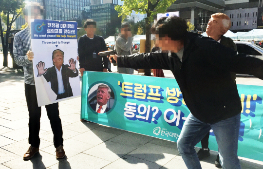 21세기 한국대학생연합 회원들이 29일 서울 종로구 주한 미국 대사관 인근 KT 광화문빌딩 앞에서 도널드 트럼프 대통령 방한 반대 집회를 열고 트럼프 대통령 얼굴 사진에 비비탄 총알을 쏘는 퍼포먼스를 하고 있다. 뉴시스