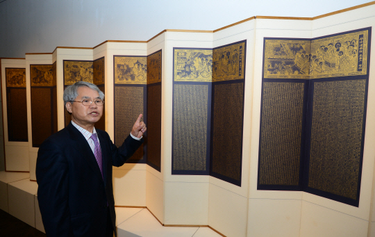 허락 작가가 묘법연화경 14곡 병풍 앞에서 금사경 작업에 대해 설명하고 있다. 병풍에는 작가가 ‘금가루 물감’으로 필사한 법화경 7만 자와 역시 직접 그린 변상도(부처님 설법 모습) 7점이 함께 담겨 있다.  김선규 기자 ufokim@