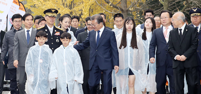 문재인 대통령이 3일 오전 충남 천안시 중앙소방학교에서 열린 제55주년 소방의날 기념식에 참석하기 위해 충혼탑에 참배한 뒤 순직 소방관 유족들과 함께 식장에 입장하고 있다. 문 대통령은 이날 기념사에서 “소방관의 건강과 공무상 재해에 대한 국가의 책임을 강화하겠다”고 약속했다. 연합뉴스