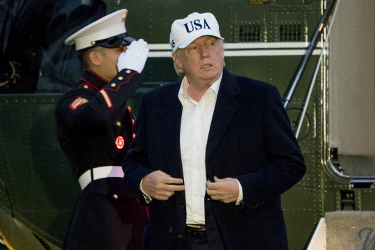 신국가안보전략 발표를 하루 앞둔 도널드 트럼프 미국 대통령이 17일 메릴랜드주의 캠프 데이비드에서 주말을 보내고 ‘USA’ 글자가 선명한 흰색 모자를 쓴 채 전용헬기인 마린 원에서 내려 백악관으로 복귀하고 있다.  AP 연합뉴스