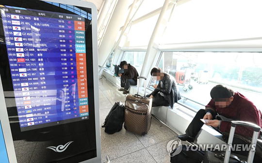 (영종도=연합뉴스) 지난 23일 기상악화에서 비롯된 항공기 지연이 사흘째 계속된 25일 오전 지연안내가 전광판에 표시되고 있는 인천공항 출국장에서 여행객들이 수속 시간을 기다리고 있다.