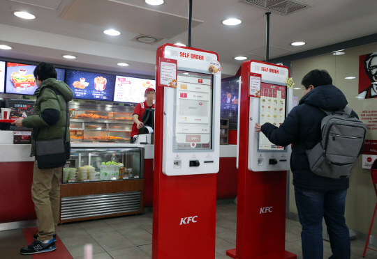 최저임금 인상으로 음식점에서 키오스크(주문받는 기계)가 종업원을 대체할 것이라는 우려가 나오는 가운데 지난 20일 서울 시내 한 패스트푸드점에서 손님이 키오스크를 통해 음식을 주문하고 있다.  연합뉴스