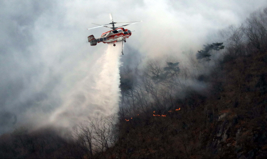 2일 오전 산림청 소방 헬기가 부산 기장군 장안읍 삼각산에서 발생한 화재를 진압하기 위해 공중에서 물을 뿌리고 있다. 연합뉴스