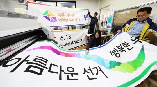6·13 지방선거를 91일 앞둔 14일 경기 수원시 팔달구 한 인쇄소에서 관계자들이 막 출력돼 나온 선거 홍보용 현수막을 점검하고 있다.  연합뉴스