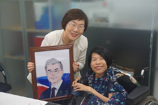 이미경 코이카 이사장이 지난 23일 베트남 장애청년 사회적기업인 ‘이미지터’의 응우옌 띠 반 대표로부터 문재인 대통령 초상화를 선물받고 있다.  코이카 제공