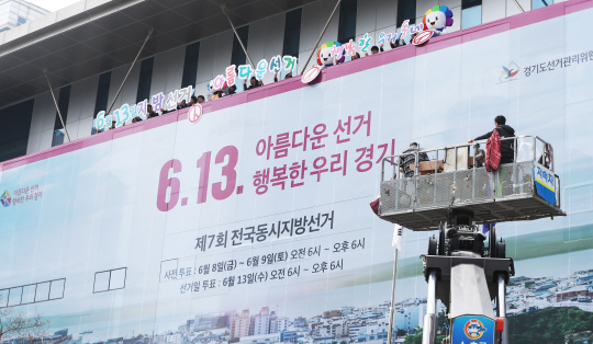 제7회 전국동시지방선거를 65일 앞둔 9일 오전 경기 수원시 경기도선거관리위원회에서 관계자들이 청사 벽면에 지방선거를 홍보하는 래핑 작업을 하고 있다. 연합뉴스