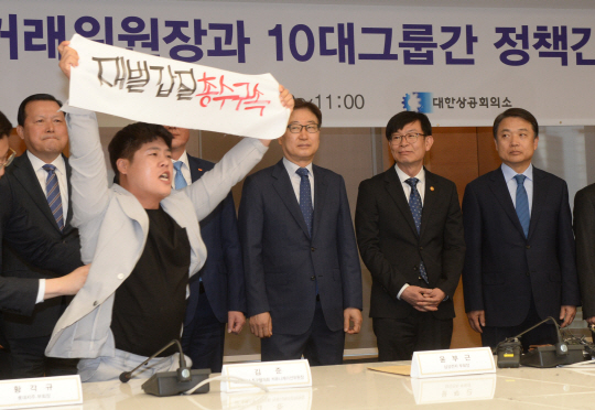 김상조(오른쪽 두 번째) 공정거래위원장과 10대 그룹 전문경영인들이 10일 오전 서울 중구 남대문로 대한상공회의소에서 개최한 정책간담회에 민주노총 금속노조 한 회원(왼쪽)이 난입해 ‘재벌 갑질 총수 구속’을 외치고 있다.