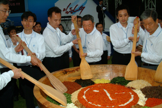 구본무(가운데) 회장이 2005년 한 해 기술 성과를 공유하는 축제 ‘스킬올림픽(현재 LG 혁신한마당)’에 참가해 임직원들과 함께 LG 로고가 장식된 대형 비빔밥을 만들고 있다.  LG제공