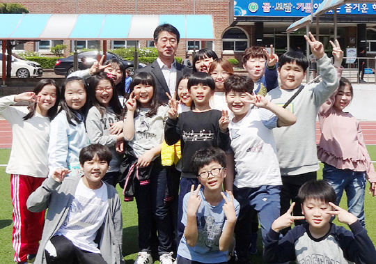 평소 운동장에서 학생들과 어울려 스스럼없이 공을 차며 소통하는 남정태 춘천 동부초등학교 교감. 점심시간에 학교 운동장을 찾았다가 주위에 몰려든 환한 표정의 학생들과 모처럼 기념촬영을 했다.  초록우산어린이재단 제공