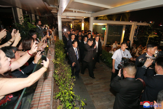 김정은 북한 국무위원장이 11일 밤 싱가포르의 여러 명소를 참관했다고 북한 노동당 기관지 노동신문이 12일 보도했다. 사진은 김 위원장이 환호하는 시민들에게 손을 흔들자 반대편에 있던 시민들이 휴대전화로 김 위원장을 촬영하는 모습.  연합뉴스