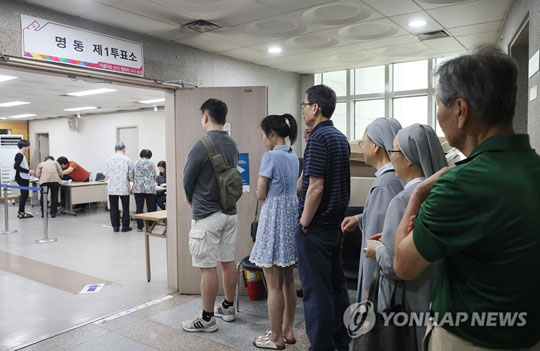 (서울=연합뉴스) 제7회 전국동시 지방선거 투표일인 13일 오전 서울 중구 명동주민센터에 마련된 명동 제1투표소에서 유권자들이 투표를 하기 위해 줄을 서서 기다리고 있다. 2018.6.13