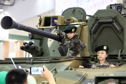 방위사업청과 국방기술품질원이 격년으로 개최하는 ‘대한민국 방산 부품·장비 대전 및 첨단국방산업전’에서 가족 관람객들이 전시된 장갑차에서 기념촬영을 하고 있다.  국방기술품질원 제공