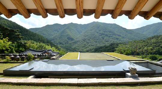 전북 완주 오성한옥마을의 한옥 고택 아원 만휴당의 다실 창밖으로 펼쳐지는 풍경. 경사의 지형을 활용해 현대식으로 건축한 미술관을 기단으로 삼아 미술관 지붕이 곧 마당이 되도록 했다. 열고 닫을 수 있도록 해놓은 미술관 지붕에 물을 담아 마당의 연못처럼 배치했다. 이 연못의 수면에는 앞산의 초록 그림자가 드리워진다.