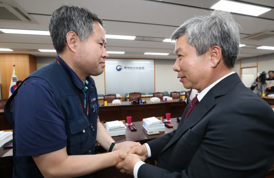 최저임금위원회의 사용자 측 이동응 위원(오른쪽)과 근로자 측인 정문주 위원이 3일 오후 정부세종청사에서 열린 9차 전원회의에 앞서 악수를 하고 있다.  연합뉴스