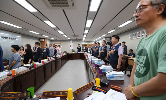 4일 세종시 정부세종청사에서 열린 최저임금위원회 전원회의에서 그동안 회의에 불참했던 근로자 위원 9명 중 한국노총 추천 위원들이 복귀해 국기에 대한 경례를 하고 있다.  연합뉴스