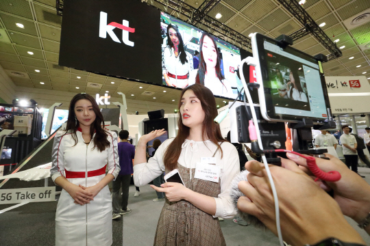 지난 5월 서울 강남구 코엑스에서 열린 ‘월드IT쇼 2018’에서 KT그룹 대학생 서포터스가 5세대(G) 네트워크를 이용해 페이스북 생중계를 하고 있다.  KT 제공