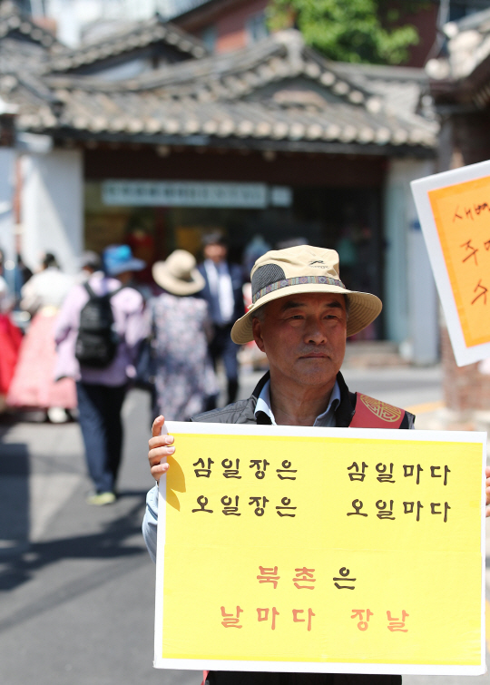 서울 종로구 북촌로에서 북촌한옥마을운영회 관계자가 관광객 방문 반대 팻말을 들고 시위를 하고 있다.  연합뉴스