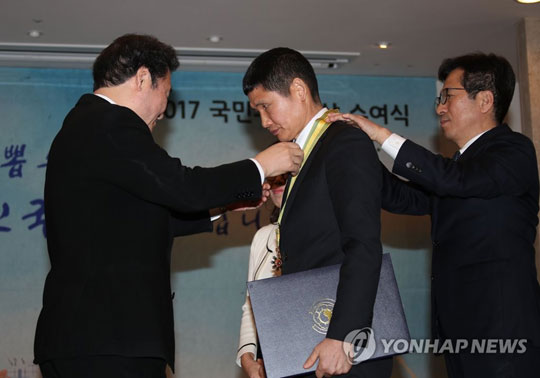 (서울=연합뉴스) 이낙연 국무총리가 31일 오후 서울 세종로 정부서울청사에서 열린 국민추천포상 수여식에서 세월호 사고현장에서 소방호스로 수십 명의 목숨을 살린 ‘파란 바지의 의인’ 김동수(54)씨에게 국민훈장 동백장을 주고 있다. 2018.1.31