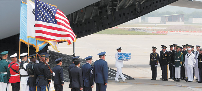 정전협정 체결 65주년을 맞은 27일, 6·25전쟁 당시 북한에서 전사한 미군 유해를 싣고 북한 원산 갈마비행장을 출발한 미군 수송기가 오산 미 공군기지에 도착했다. 미군 병사가 유엔기로 감싼 나무관을 운구하고 있다. 사진공동취재단
