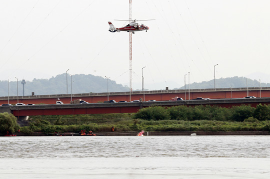 13일 오전 경기 김포시 고촌읍 신곡수중보 인근에서 소방헬기가 전날 전복 사고로 2명의 구조대원이 실종된 소방구조대 보트 인양 작업을 하고 있다. 연합뉴스