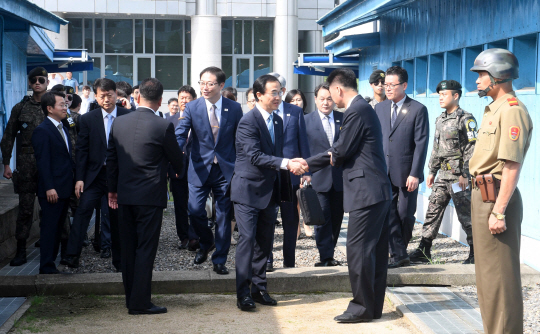 조명균(가운데) 통일부 장관이 13일 오전 판문점 북측 통일각에서 열린 남북 고위급회담에 참석하기 위해 군사분계선을 넘어 북측 관계자와 악수하고 있다. 사진공동취재단