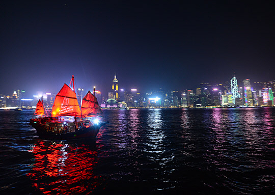 홍콩 빅토리아 항구 앞바다를 미끄러지듯 항해하는 아쿠아루나 유람선. 정크 보트의 모습을 본뜬 유람선의 붉은 돛의 선명한 색감이 인상적이다.