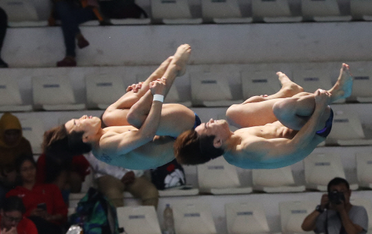우하람(오른쪽)과 김영남(이상 한국체육진흥공단)이 28일 인도네시아 자카르타의 겔로라 붕 카르노 수영장에서 열린 2018 자카르타-팔렘방아시안게임 다이빙 남자싱크로나이즈드 3m 스프링보드 결선에서 오차 없는 연기를 펼치고 있다.  연합뉴스