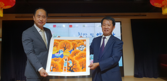 엄재권(왼쪽) 한국민화협회 회장과 위웨이팅 산둥성 칭저우시 농민화협회 회장이 5일 전시 개막식에서 화사한 색감이 돋보이는 농민화를 함께 들어 보이고 있다.