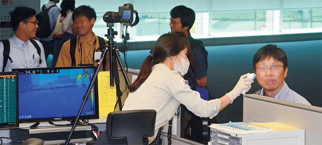 10일 오전 인천국제공항 제2여객터미널 입국장에서 검역관이 입국 승객들의 체온을 확인하고 있다. 메르스(중동호흡기증후군) 환자인 A(61) 씨가 지난 7일 인천공항 검역대를 아무 의심 없이 통과한 뒤 4시간 만에 메르스 의심환자로 분류되면서 검역 당국의 부실한 대응이 도마에 올랐다.