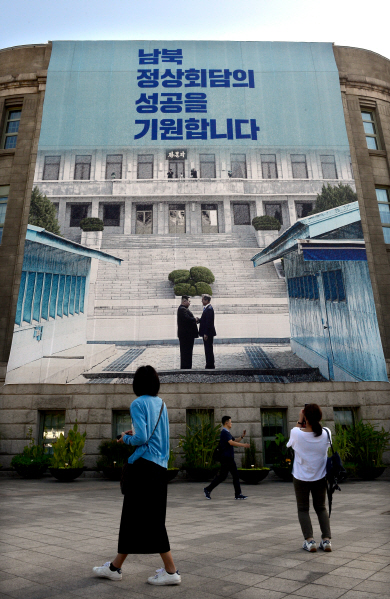 12일 오전 세종대로 서울광장에서 시민들이 시민청 외벽에 걸린 남북정상회담 성공 기원 대형 현수막을 보고 있다.