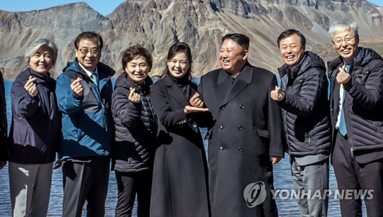 (서울=연합뉴스) 북한 김정은 국무위원장과 리설주 여사가 20일 백두산 천지에서 남쪽 수행원들과 기념사진을 찍고 있다. 처음에는 손을 내리고 있었으나, 강경화 외교부 장관으로부터 “남쪽에서 유행하는 손가락 하트를 해보자”는 제안을 받고 따라하고 있다. 리설주 여사가 김 위원장의 손을 받치고 있다. 2018.9.23 [청와대 제공]