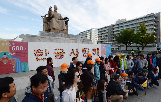 한글날을 앞둔 8일 오전 서울 종로구 광화문 광장의 세종대왕상 앞에 꽃으로 ‘한글 사랑해’라고 새긴 벽보를 배경으로 외국인 관광객들이 기념사진을 찍고 있다.