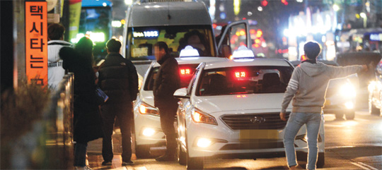 19일 밤 서울 강남역 인근에서 빈 택시가 있는데도 불구하고 한 시민이 도로 안쪽까지 나가 택시를 잡고 있다.