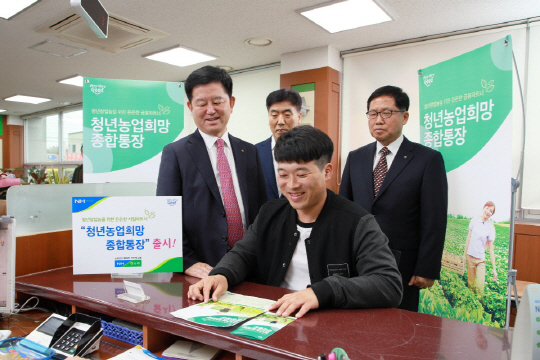 농협 상호금융 창구에서 한 청년(앞쪽)이 지난 4월 출시한 청년농업희망 종합통장 안내문을 보고 있다.  농협중앙회 제공