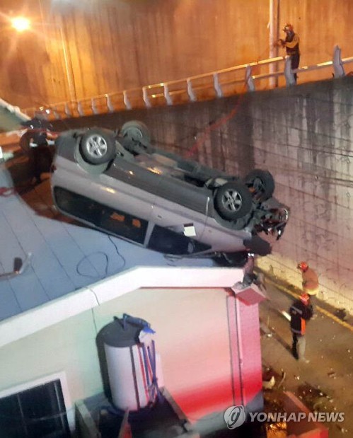 (부산=연합뉴스) 1일 오전 부산 사하구 감천동 이면도로를 달리던 스타렉스 승합차가 가드레일을 뚫고 도로 아래 주택 옥상에 떨어져 119구조대원들이 구조작업을 벌이고 있다. [부산경찰청 제공]