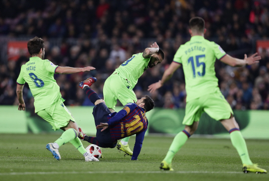 FC 바르셀로나의 리오넬 메시(가운데)가 18일 오전(한국시간) 스페인 바르셀로나의 캄프누에서 열린 레반테와의 코파 델 레이 16강 2차전에서 수비수 3명의 집중 견제를 받으면서 넘어지고 있다.  AP연합뉴스