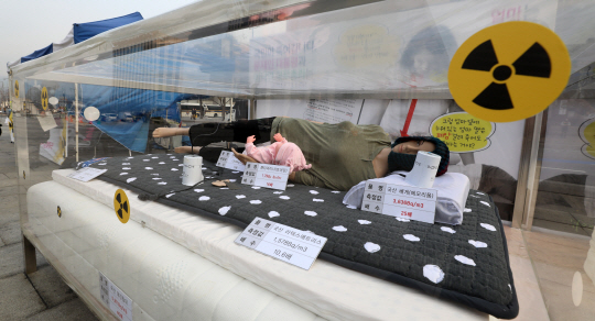 지난해 말 서울 종로구 광화문광장에서 환경보건시민센터가 시중에서 판매 중인 제품을 대상으로 방사선 라돈 측정값을 써놓은 제품과 마네킹을 전시하고 있다. 이 센터는 메모리폼 베개, 라텍스 매트릭스 등 일부 국산 제품에서 라돈이 검출된다며 정부가 해당 제품을 공개해 국민건강권 보호에 나서야 한다고 촉구했다.   뉴시스