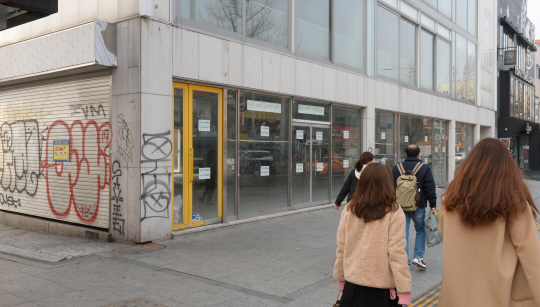 경기 침체로 서울 주요 상권의 빈 상가가 늘고 있는 가운데 27일 오전 출근을 서두르고 있는 시민들이 용산구 이태원동 한 건물의 빈 점포 앞을 지나가고 있다.