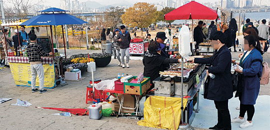 지난 17일 서울 여의도 한강공원 입구인 천상의 계단에서 불법 노점 상인들이 닭꼬치 등 거리 음식을 판매하고 있다.